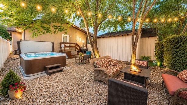 Ein Garten mit Whirlpool, Gartenmöbeln, Lichterketten und einer Pergola.