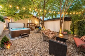 A backyard with a hot tub, outdoor furniture, string lights, and a pergola. - Guest Favorite! Hot Tub, Huge Kitchen, Fenced Yard, Firepit, & BBQ in Great Area (Price)