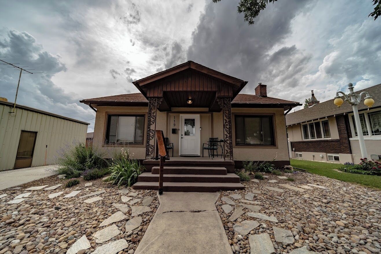 A two-story house with a front porch, a mailbox, and a stone pathway leading to the entrance.
