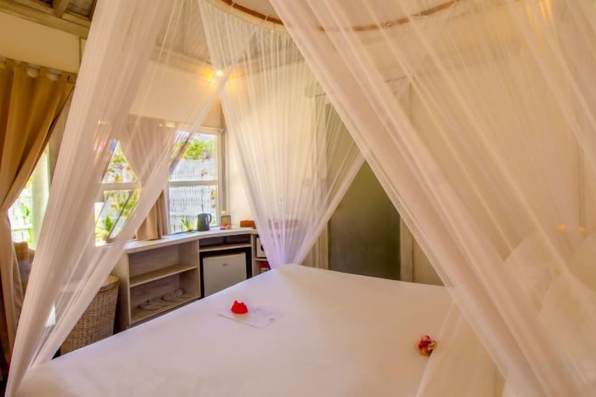 Una habitaci ón con cama bajo dosel, un escritorio con silla y ventana con vista.