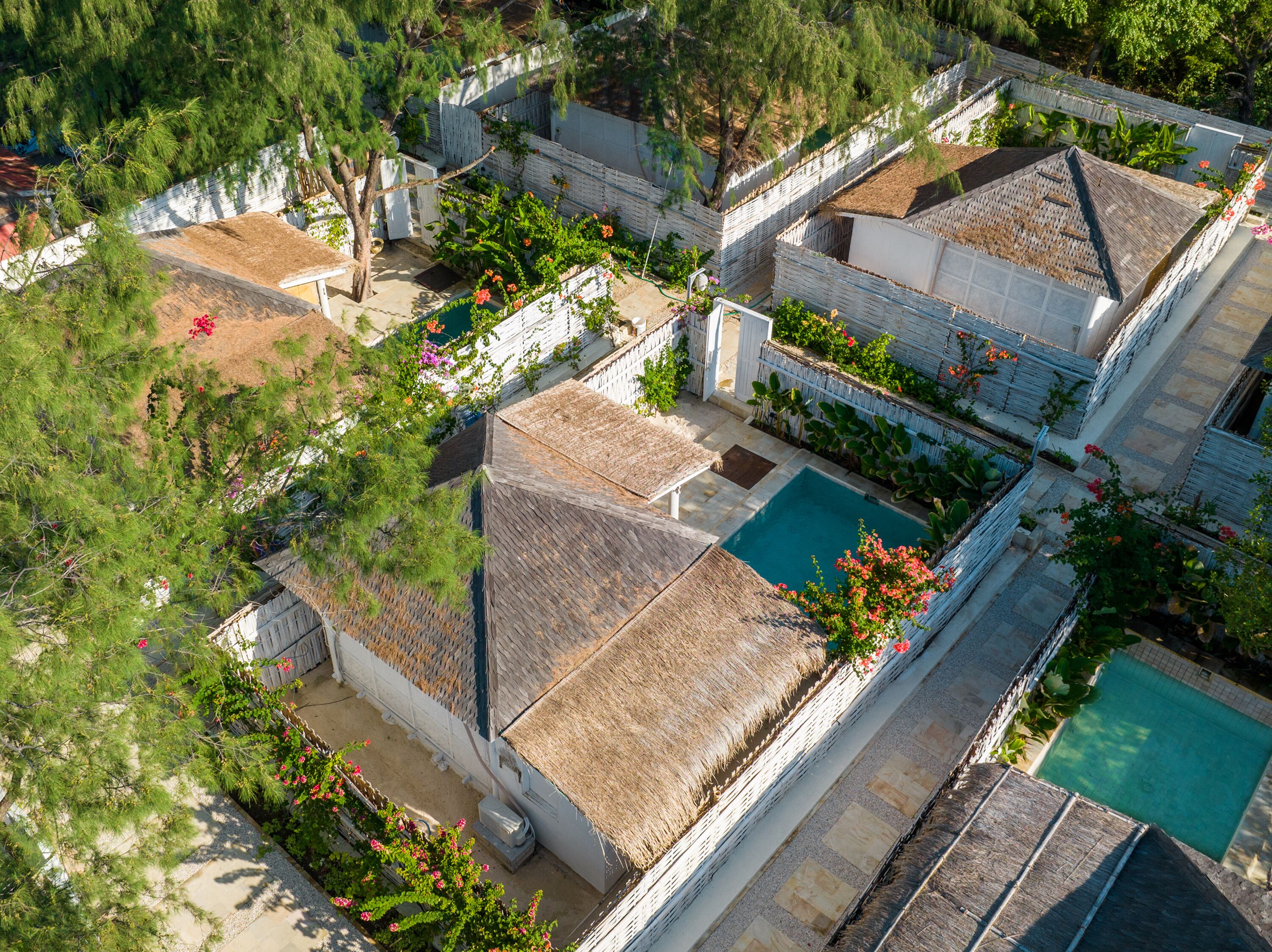 An aerial view of a residential area with multiple houses, a swimming pool, and lush greenery.