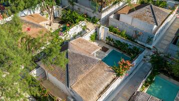 An aerial view of a residential area with multiple houses, a swimming pool, and lush greenery.