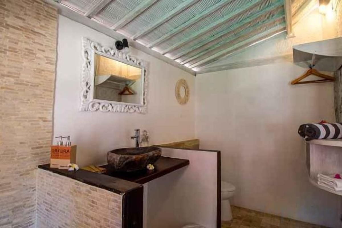 Un baño con un lavamanos de piedra, un espejo con marco decorativo y un perchero para toallas.