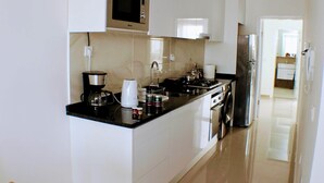 A modern kitchen with a microwave, coffee maker, kettle, and refrigerator. - Kingfisher Plateau. 2A Apt on Rua Pedonal. Praia Central_ Near cafes & shops (Praia)