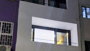 A modern two-story building with large windows and a visible staircase leading to the entrance. - Kingfisher Plateau. 2A Apt on Rua Pedonal. Praia Central_ Near cafes & shops (Praia)