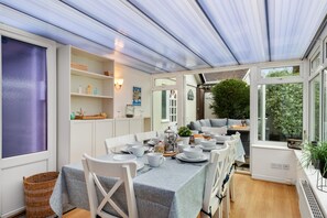 Enjoy a casual meal in this spacious dining area with a glass ceiling, adjacent seating area, and potted plant.
