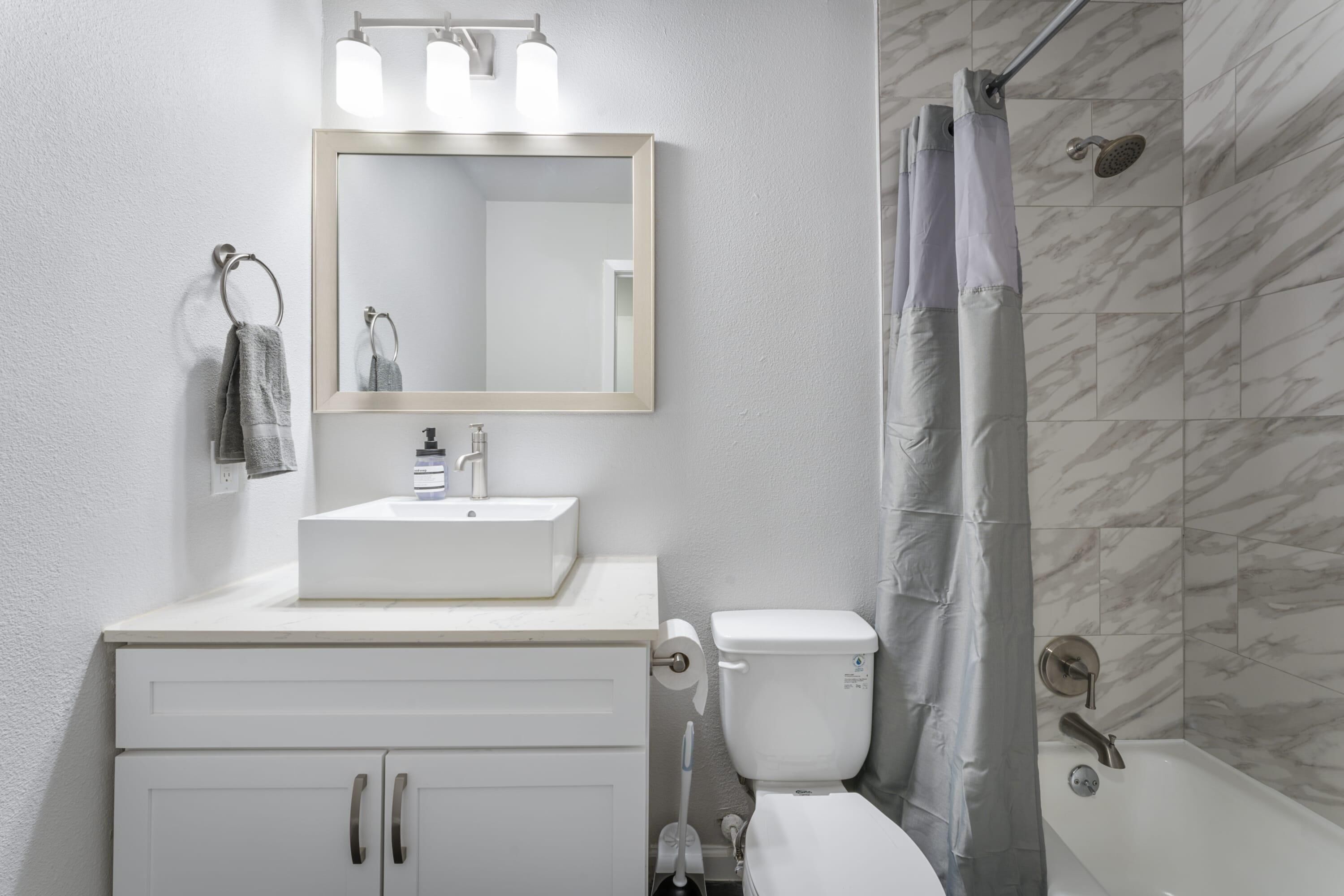 Une salle de bain moderne avec un lavabo blanc, un miroir et des toilettes.