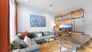Un salon moderne avec un canapé d’angle, une table basse et un téléviseur fixé sur un cadre en bois.