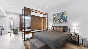Une chambre moderne avec un grand lit, un bureau et une vue sur la ville.