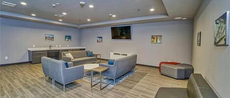 A spacious living area with a sofa, coffee table, and a small kitchen area with a sink and cabinets.