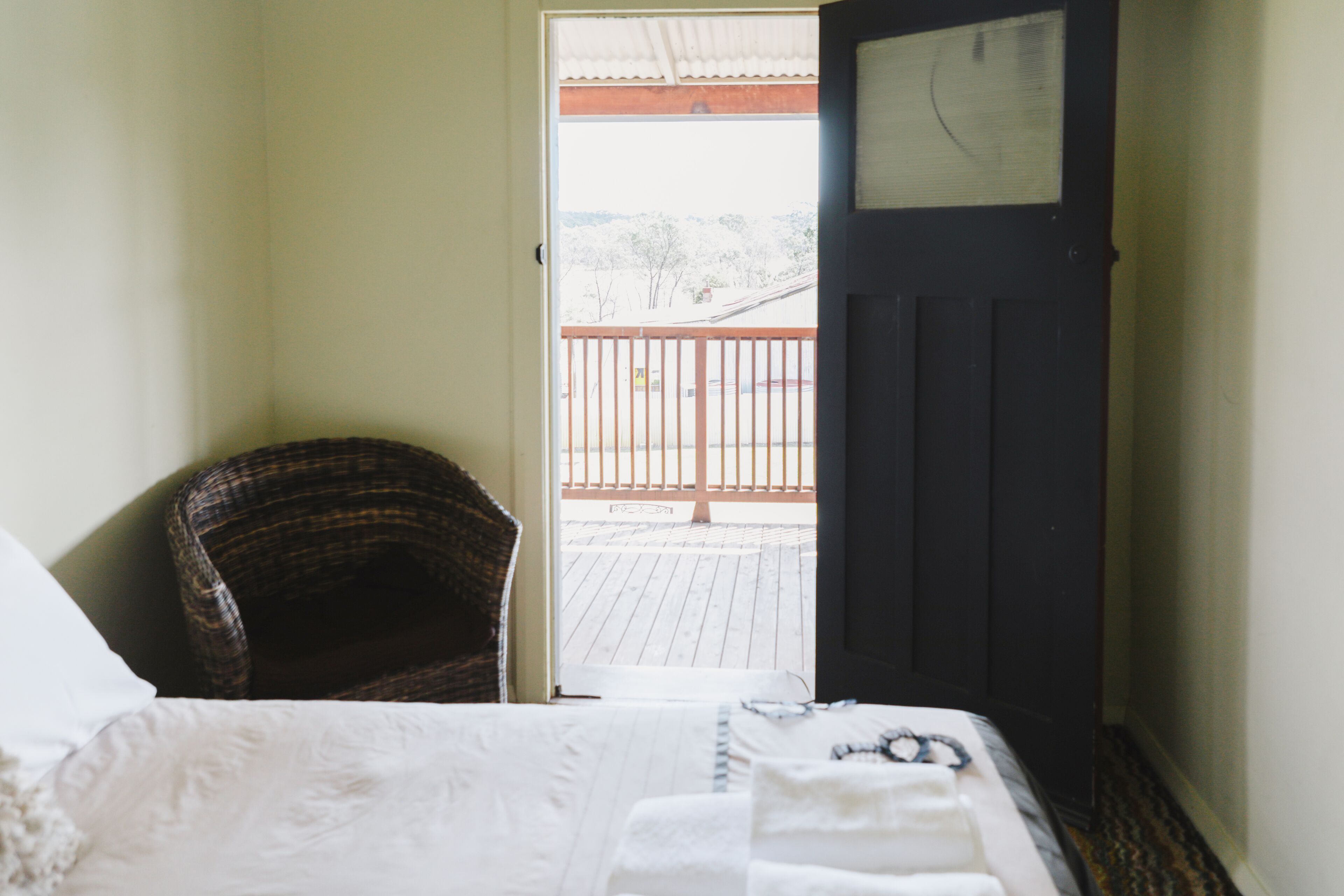 Une chambre à coucher avec un lit, une chaise et une porte donnant sur un balcon.