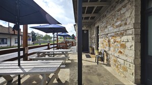 An outdoor patio with stone flooring, wooden picnic tables, and blue umbrellas. - Royal Hotel Capertee (Capertee)