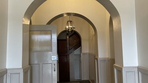 A hallway with an arched ceiling, a patterned carpet, and a door with a metal handle. - Royal Hotel Capertee (Capertee)