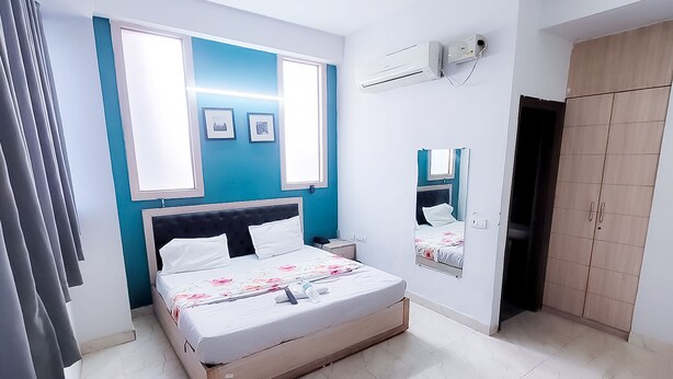 Um quarto com cama, ventilador de teto, guarda-roupa e espelho.