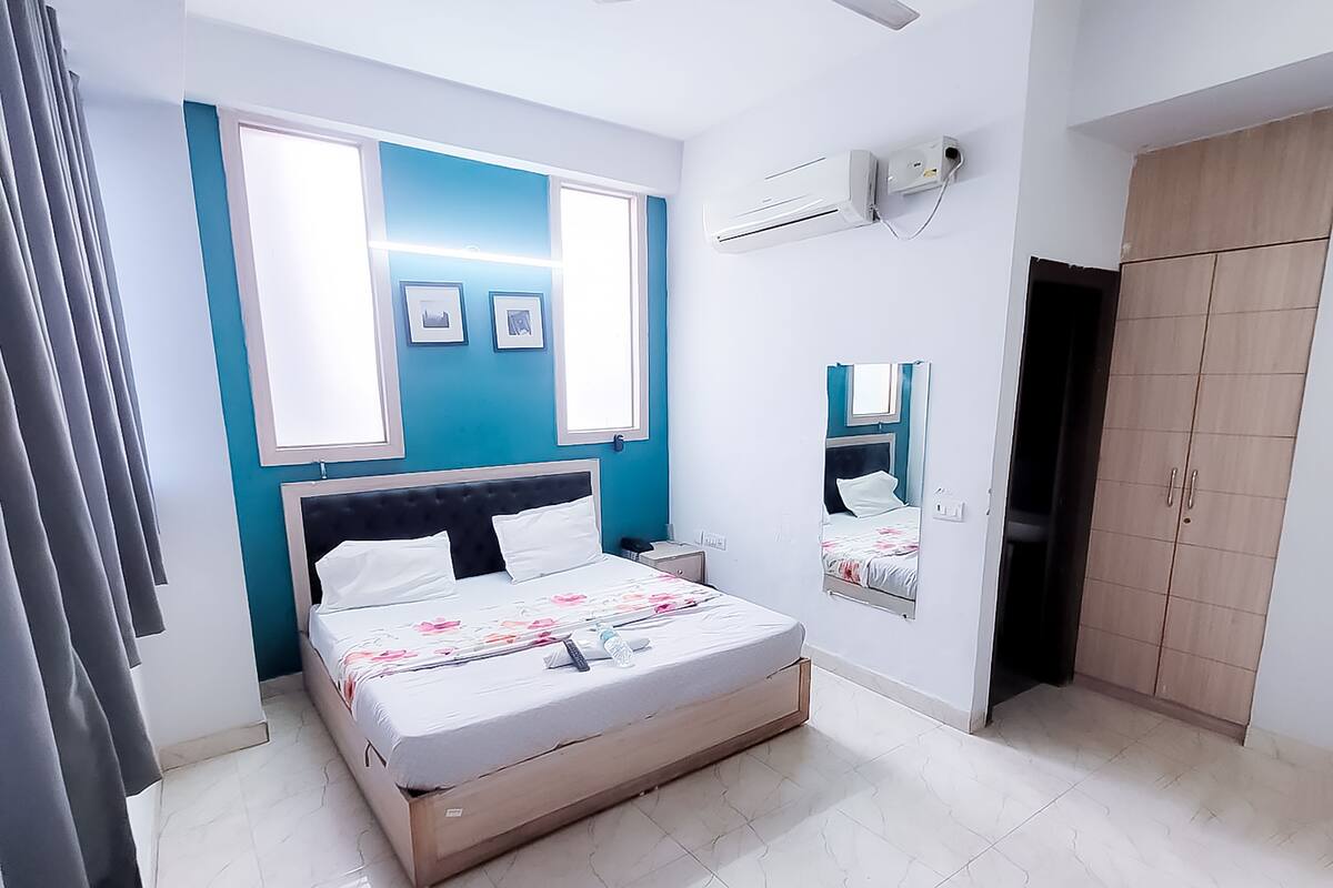 A bedroom with a bed, a ceiling fan, a wardrobe, and a mirror.