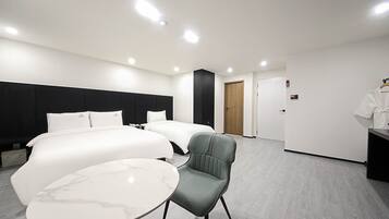 Habitación de hotel con dos camas, un escritorio, una silla y una mesita.
