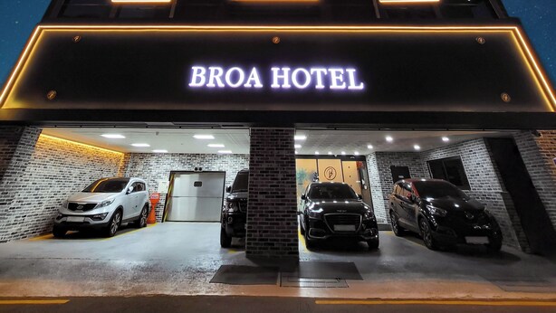 The exterior of the Broa Hotel with a modern design, featuring a prominent illuminated sign and a brick facade. - Busan Seomyeon Broa Hotel (Busan)