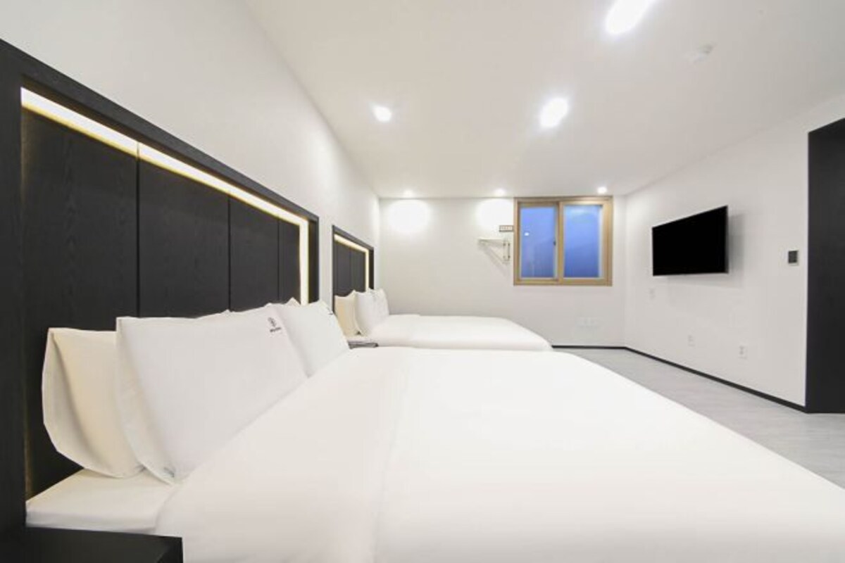 A modern hotel room with a large bed, a flat-screen TV, and a window with a view.