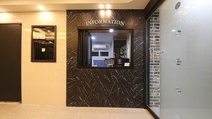 A reception area with a marble wall, an information desk, and a glass partition. - Busan Seomyeon Broa Hotel (Busan)