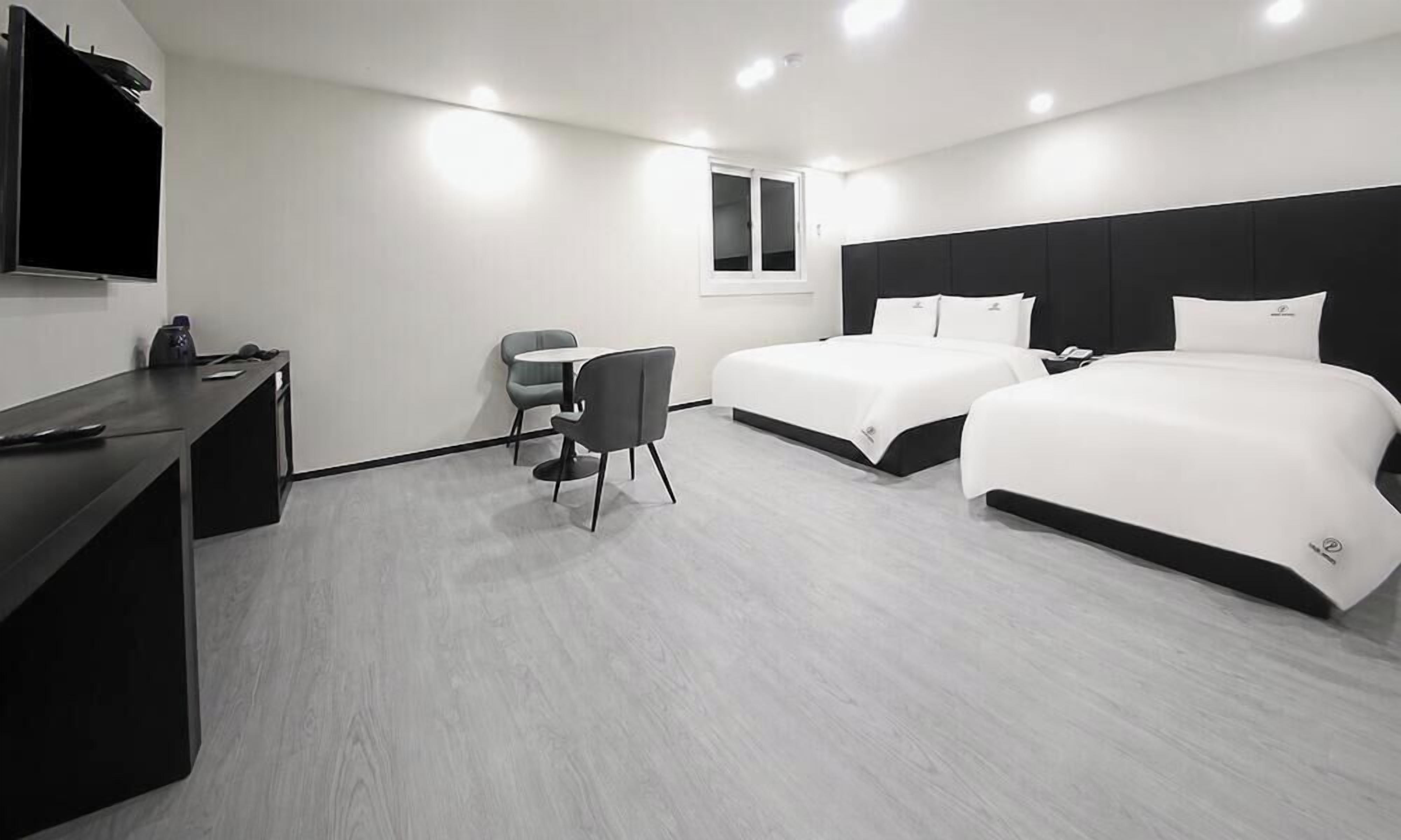 A modern hotel room with a large bed, a desk, and a TV.