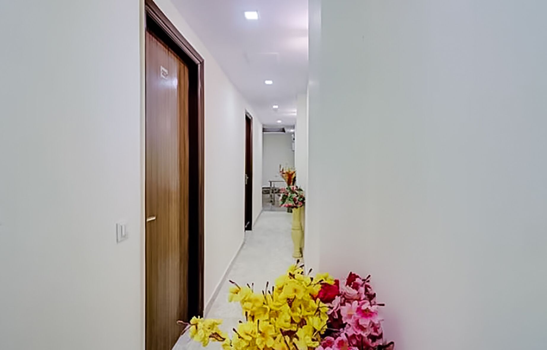 A hallway with wooden doors and a vase of flowers.