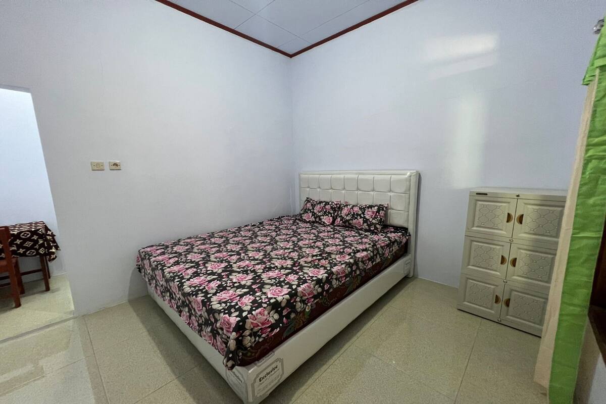 A small, neatly arranged bedroom with a bed, a chair, and a wardrobe.