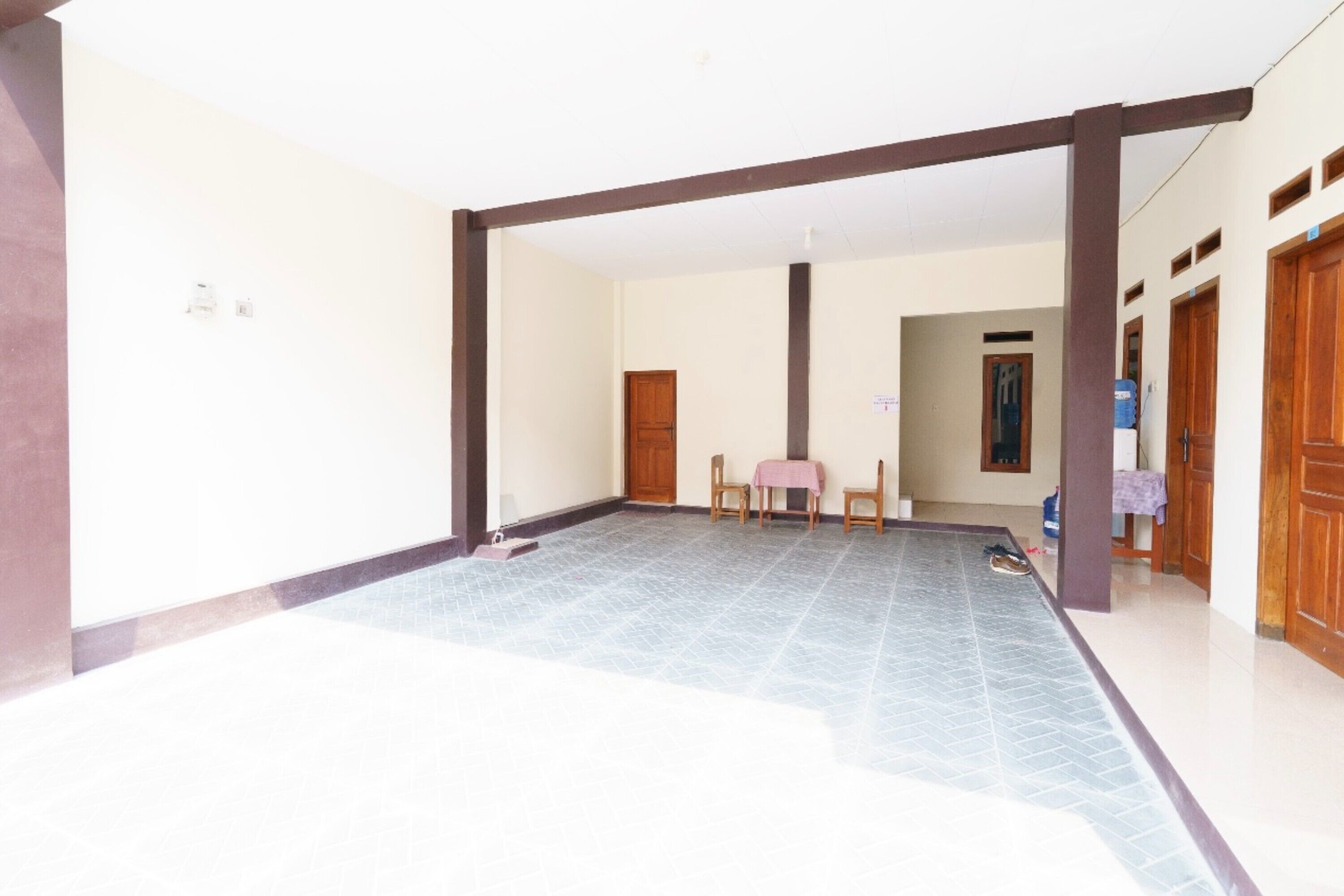 A spacious room with a tiled floor, a wooden door, and a small table with chairs.