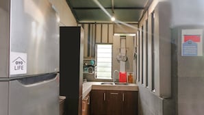A compact kitchen with a stainless steel refrigerator, wooden cabinets, and a sink.