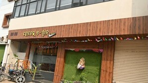 A building with a wooden facade, a green awning, and a closed shutter door. - Hotel A One Luxury (Puri)