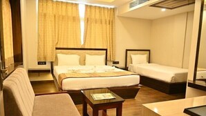 A hotel room with a large bed, a smaller bed, a sofa, a desk, and a mirror. - Hotel A One Luxury (Puri)