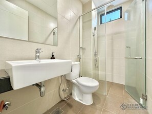 Een moderne badkamer met een douchecabine van glas, een wit wastafelmeubel en een toilet.