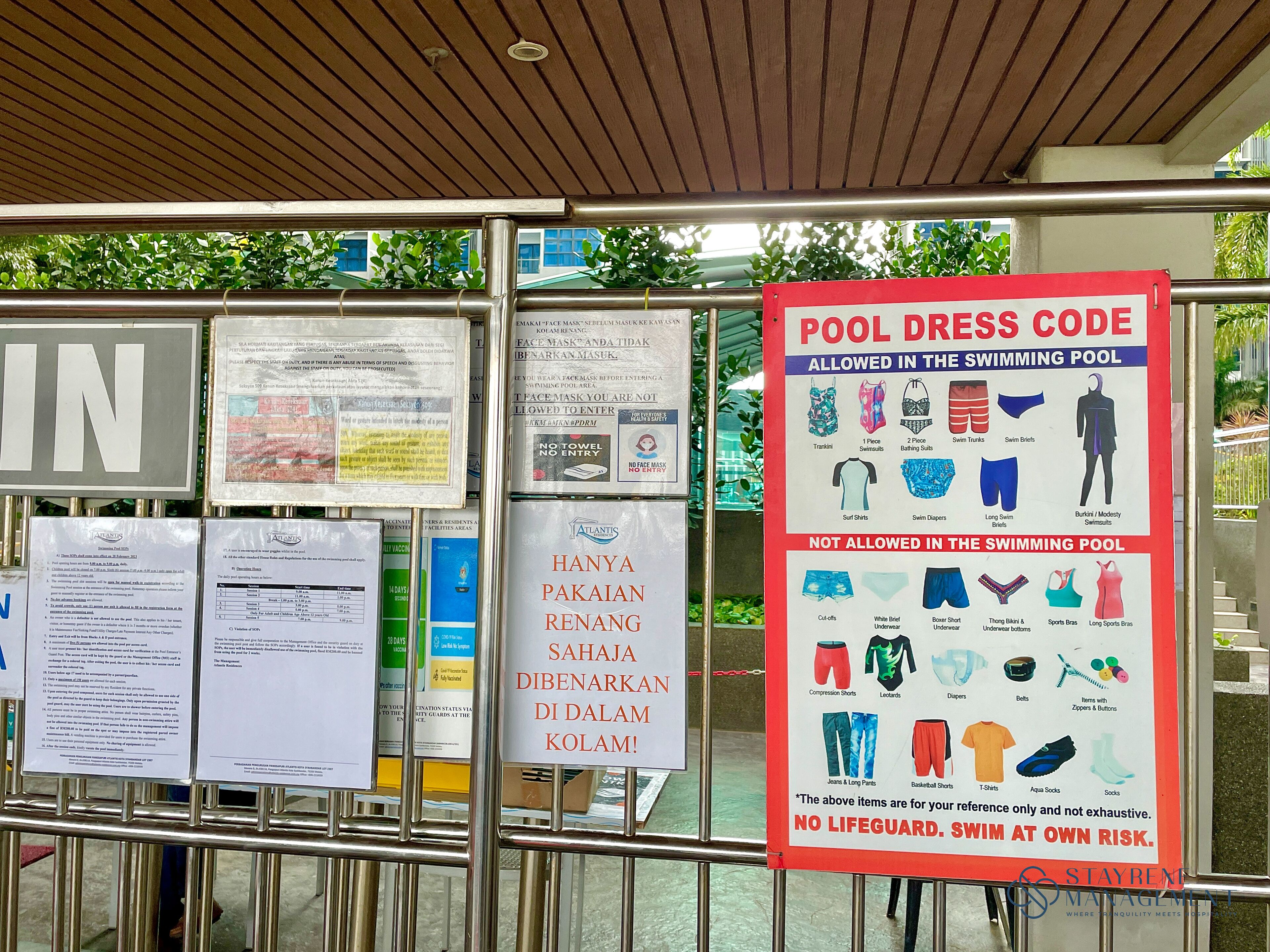 A pool area with a 'Pool Dress Code' sign detailing allowed and not allowed swimwear.