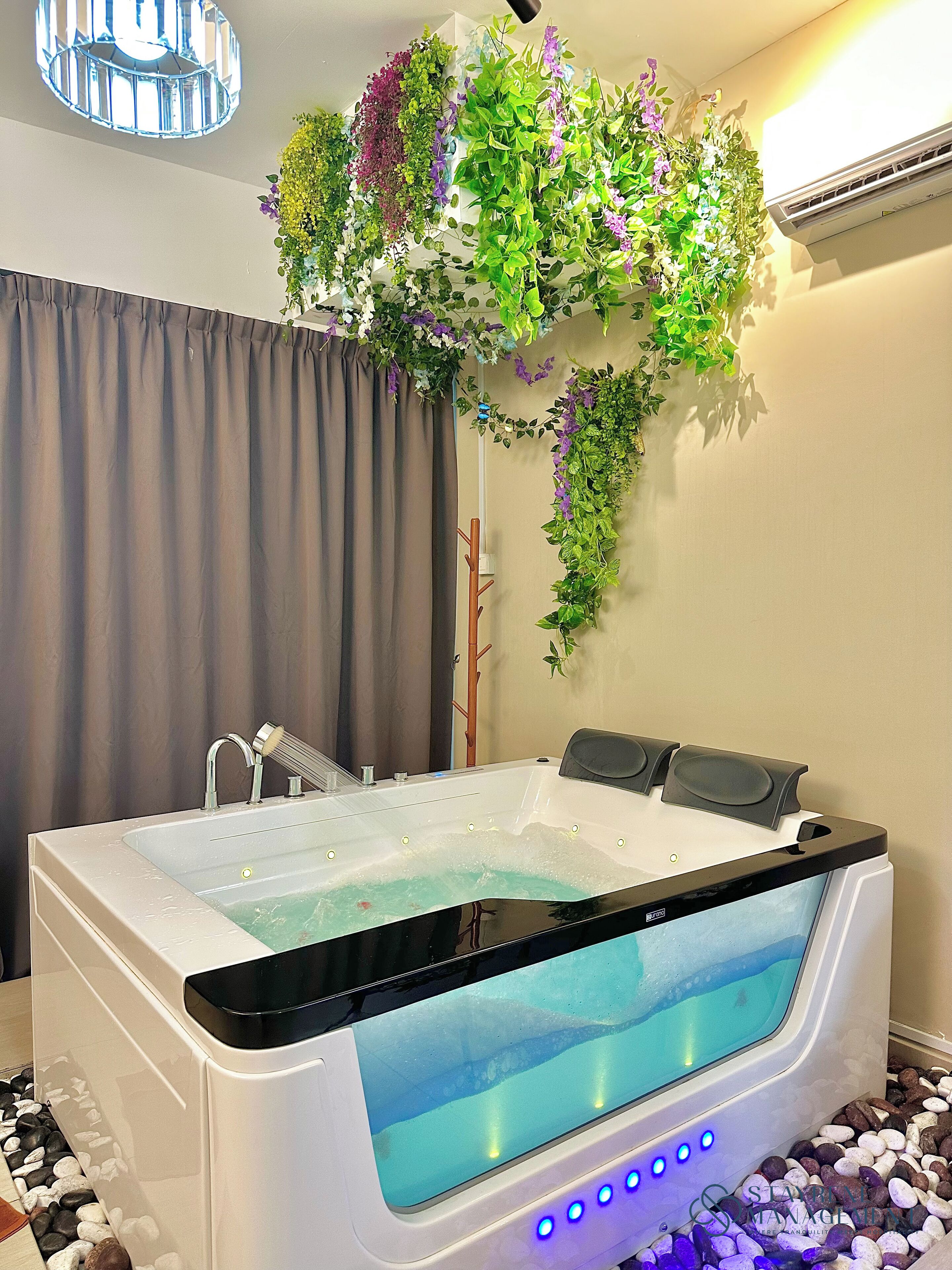 Ein modernes Badezimmer mit einer großen Badewanne, einer Dusche und einer wandmontierten Pflanzengruppe.