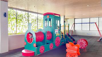Un área de juegos infantiles con un colorido tren y un columpio.