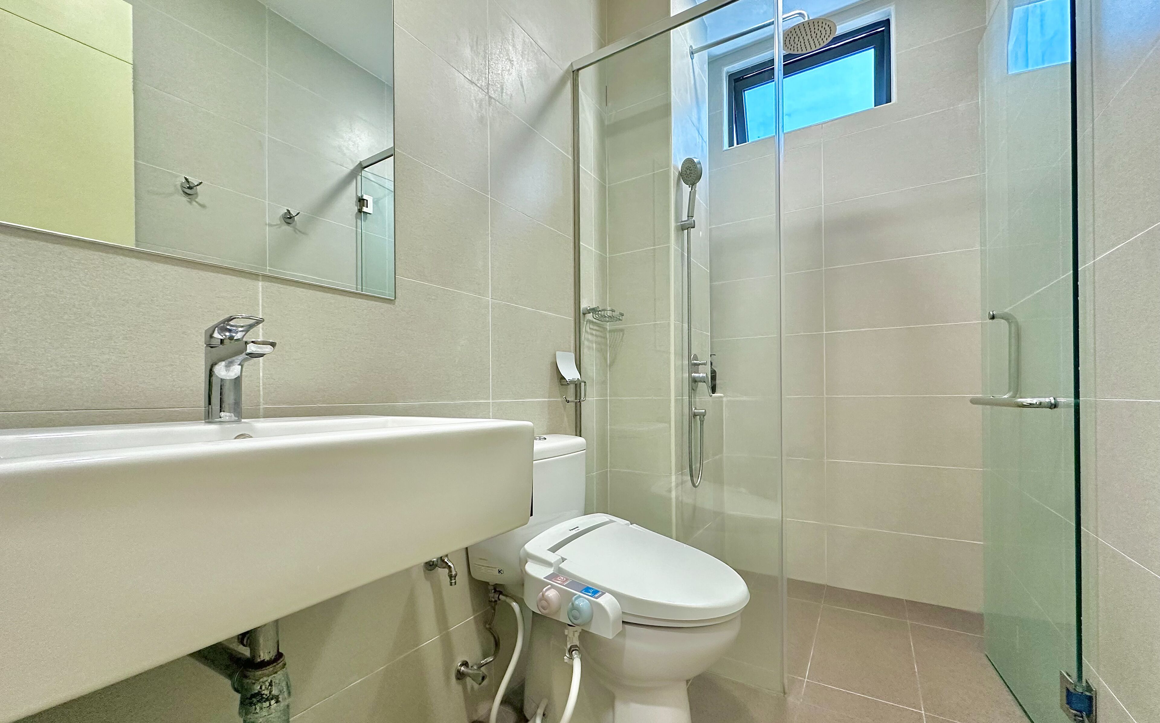A modern bathroom with a glass-enclosed shower, a white sink, and a toilet.