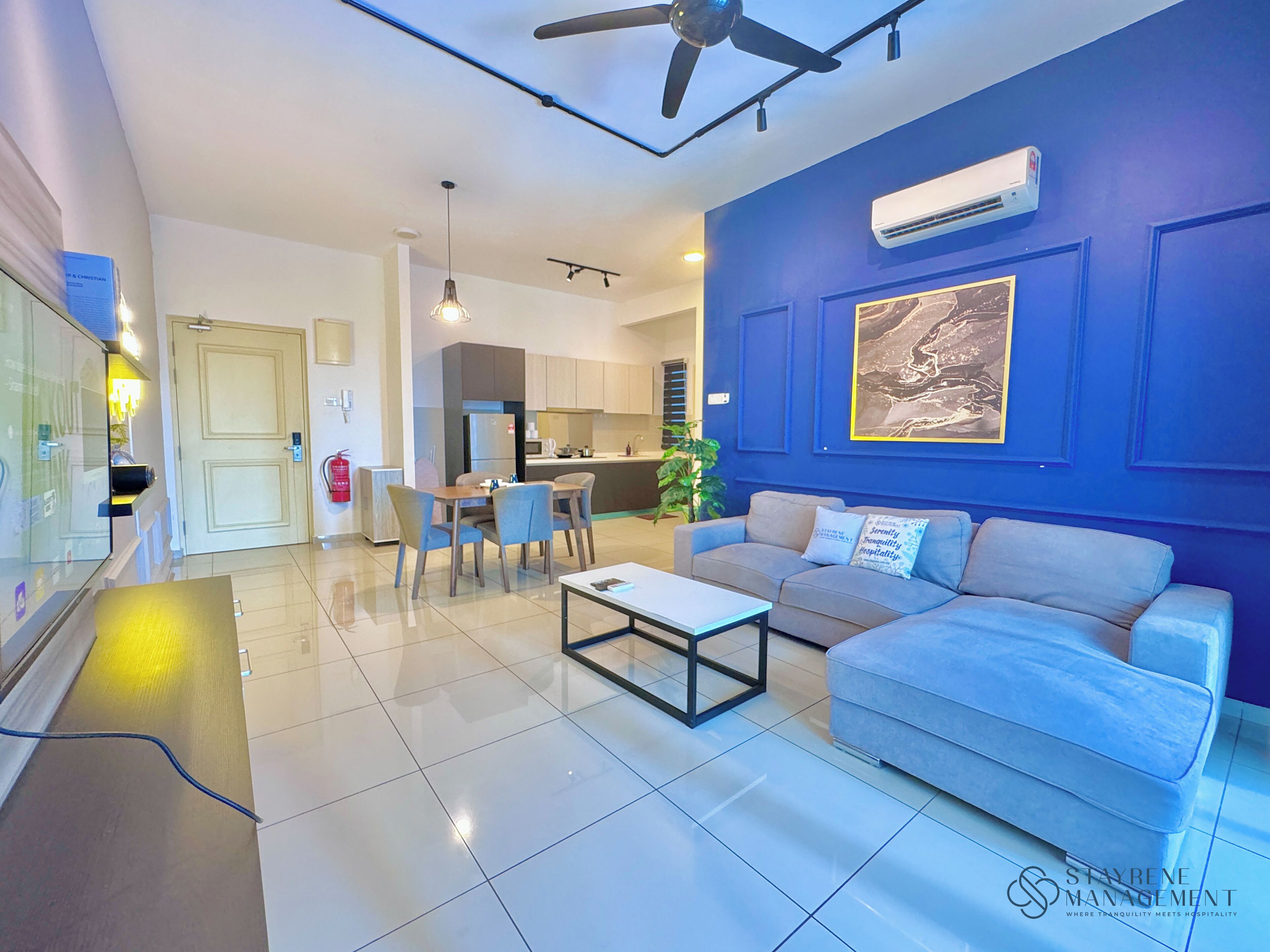 A modern living room with a blue accent wall, a sofa, a coffee table, and a dining area with chairs.