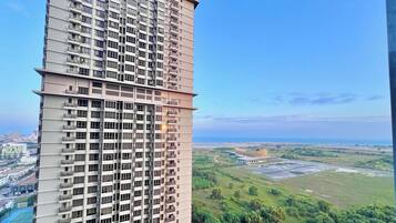 Um edifício alto com várias varandas e vista para uma paisagem verde e a costa distante.
