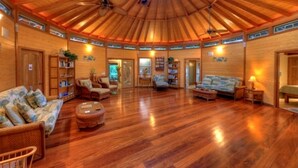 Amplia sala de estar con piso de madera, techo alto y una distribución central de los asientos.