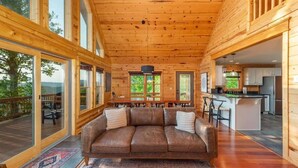 L'intérieur d'un chalet en bois, avec un canapé, une table à manger et un coin cuisine.