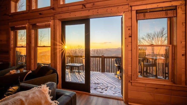 Un intérieur de chalet chaleureux avec une terrasse en bois et de grandes fenêtres.