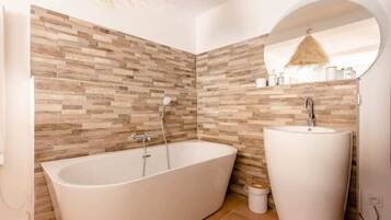 Une salle de bain moderne avec une baignoire sur pieds, un lavabo sur colonne et un mur à texture.
