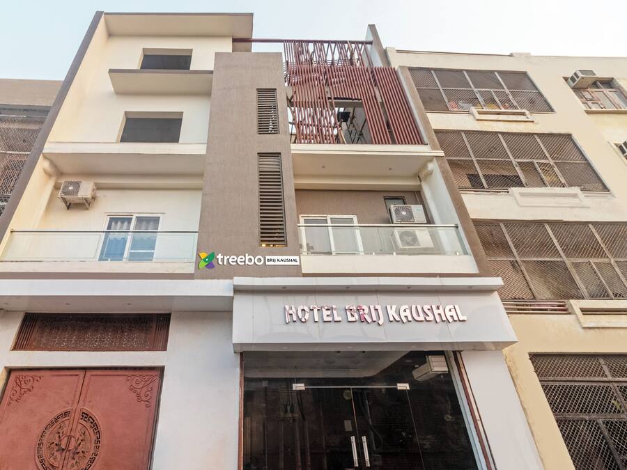 A hotel with a modern facade, featuring a prominent entrance with a large door and a balcony with a glass railing.