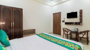 A hotel room with a bed, a desk with a chair, a television, and a wardrobe.