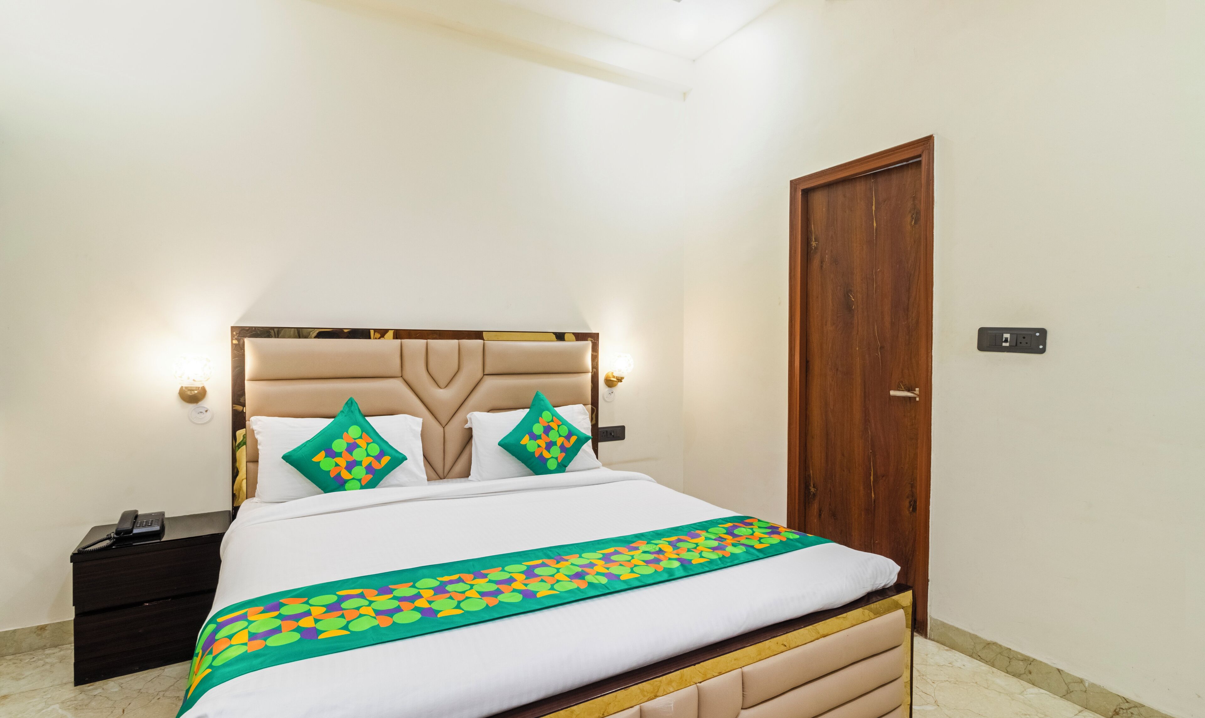 Un lit bien fait, avec une couvre-lit à motifs, une tête de lit en bois et deux coussins décoratifs.