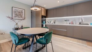 A modern kitchen with a central island, a dining area with a round table and chairs, and a pendant light. - Elegant & Serene 2BD Flat W/roof Terrace Hoxton! (London)