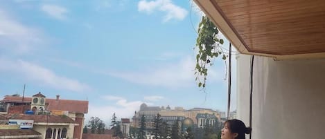 A balcony with a view of a cityscape, including buildings and a clear sky.