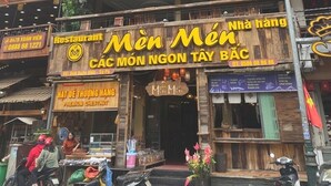A multi-story building with various signs, including a prominent 'Men Men' restaurant sign. - Tung Lam Hotel Sapa - by Bay Luxury (Sa Pa)