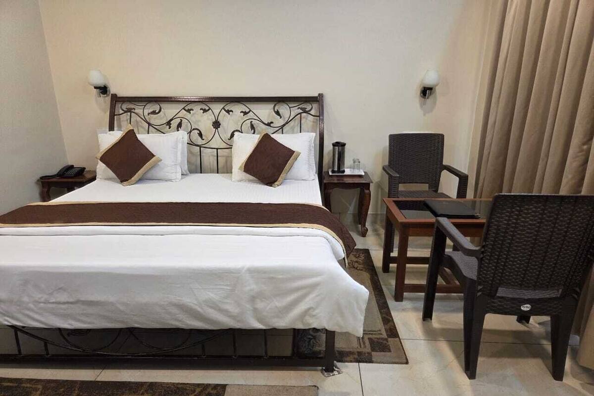 Una habitación de hotel con cama, mesitas de noche, una silla y un escritorio.
