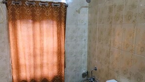 A bathroom with a shower curtain, a toilet, and a bidet. - Rose Cottage A Heritage Retreat (Abu Road)