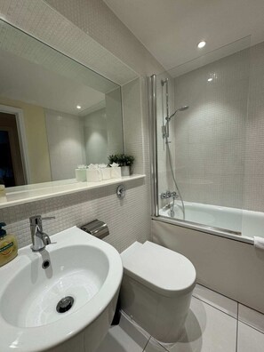 A modern bathroom with a white sink, toilet, and glass-enclosed shower.
